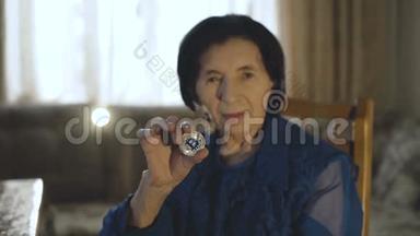 一位微笑的老妇人手持一<strong>枚</strong>银币在镜头前的画像